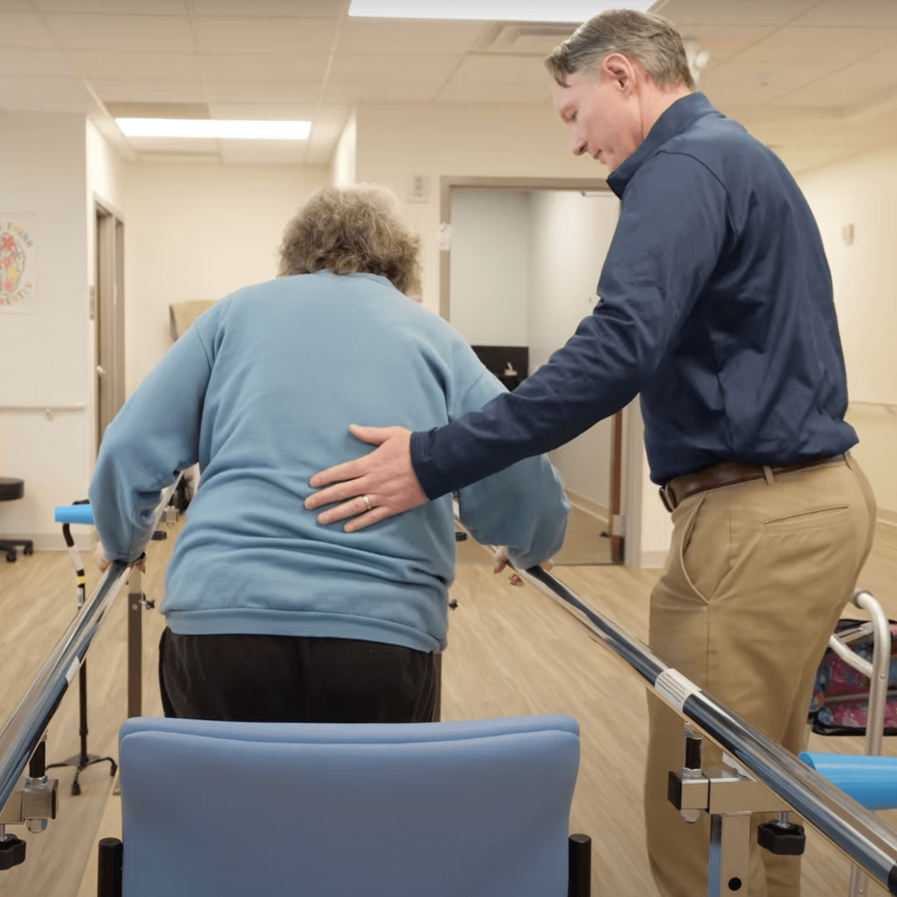 male PT helping elderly woman practice walking